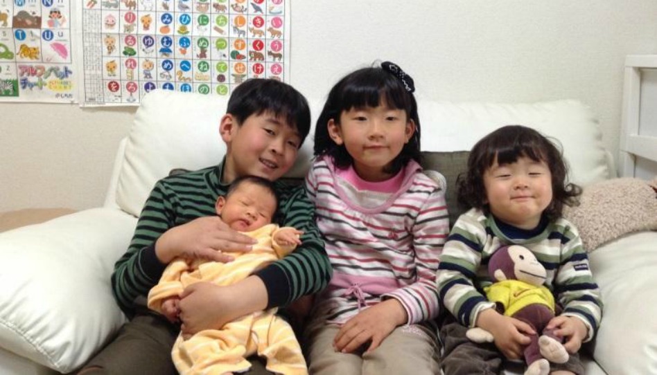 ４人の子どもがカウチに幸せそうに座っている
