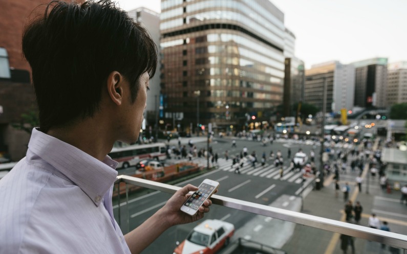 町中で携帯を手にする男性