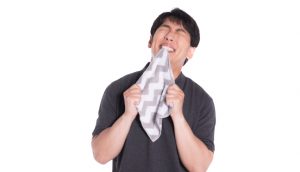 イライラしてハンカチをかむ男性