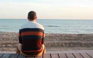 砂まで座っている後ろ姿の男性