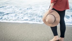 砂浜の波打ち際を裸足で歩く女性