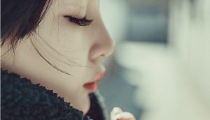 目を閉じて手を組んで祈っている横顔の女性