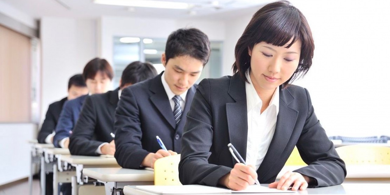 並んだ机で試験を受ける人々