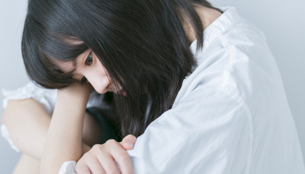 心の葛藤で悩みうずくまっている女性