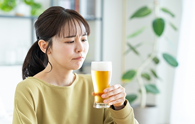 昼間の部屋で飲酒に悩む女性