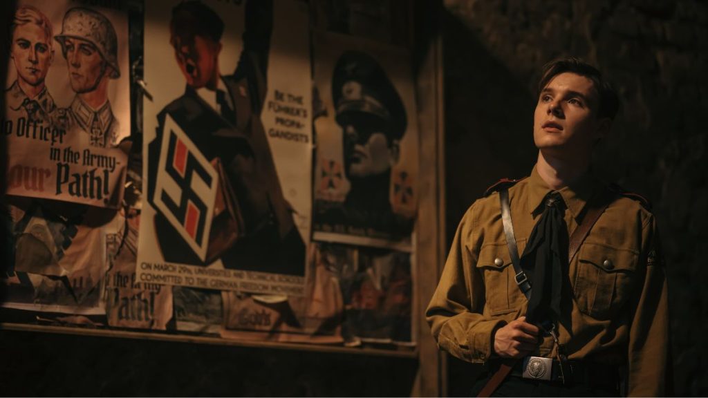 ナチスのポスターの前に立つヒューベナー 映画「真実と反逆」より